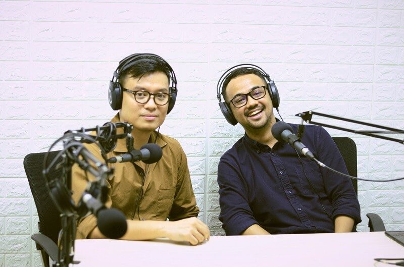Pangeran Siahaan dan Tio Prasetyo berpose di ruangan berdinding putih sambil mengenakan headphone